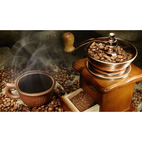 فنجان قهوه در کنار دستگاه آسیاب قهوه
